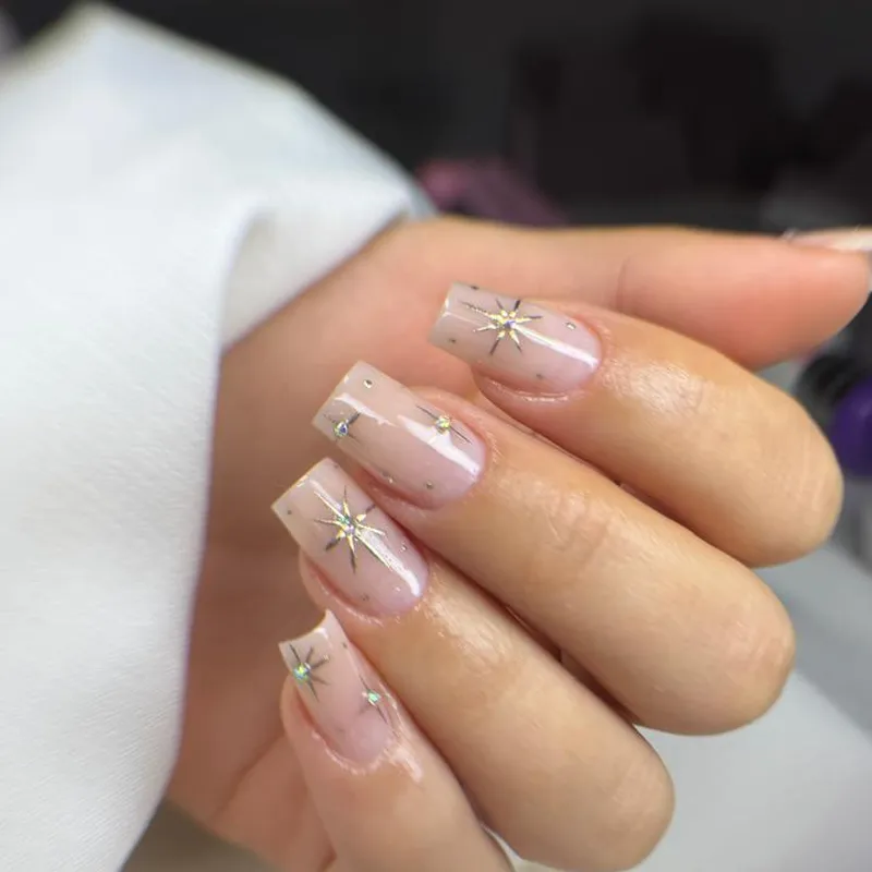 Unhas nude com nail art de estrelas e aplicação de pedras